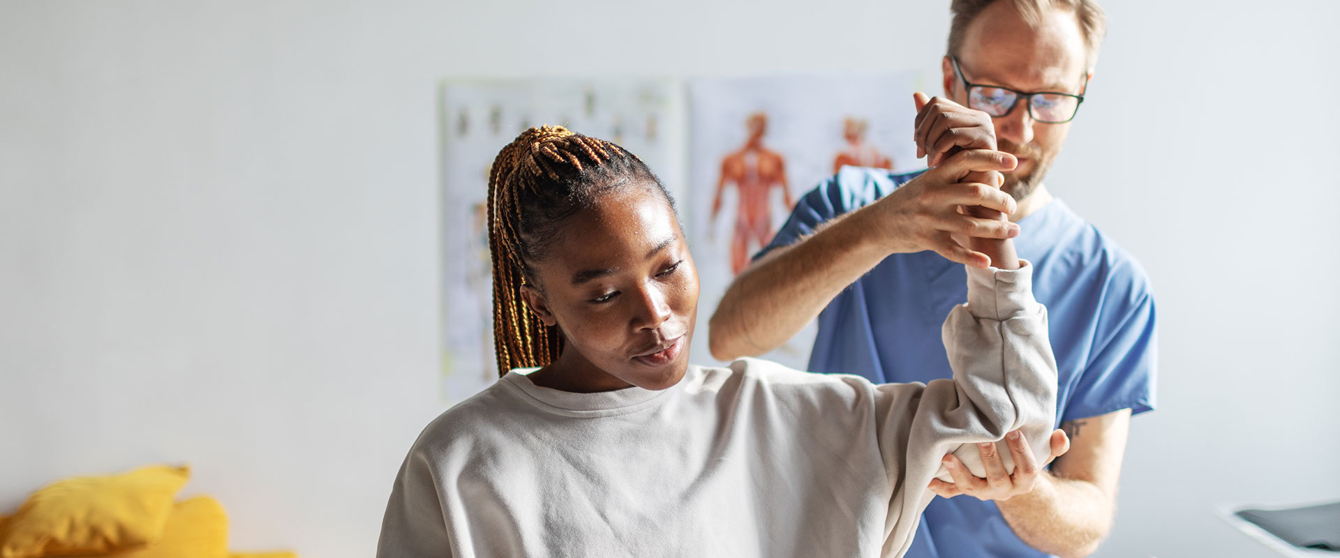 Physical therapist helping young black woman with her shoulders